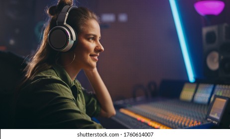 Stylish Female Audio Engineer / Producer Working in Music Record Studio, Uses Headphones, Mixer Board, Control Desk to Create New Song. Creative Artist Musician - Powered by Shutterstock