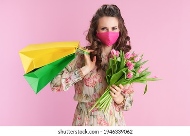 stylish female in floral dress with tulips bouquet, pink mask and shopping bags isolated on pink. - Powered by Shutterstock