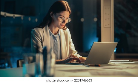 Stylish Female Working on Laptop Computer in a Company Office in the Evening. Young Project Manager Browsing Internet, Writing Tasks, Developing a Marketing Strategy for a Financial Institution. - Shutterstock ID 2231746663