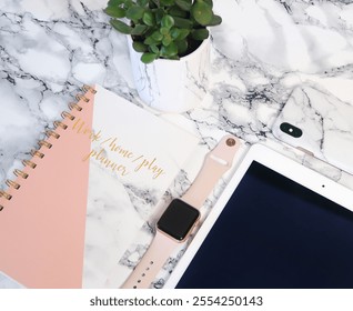 A stylish flat lay featuring a marble desk, pink and white planner, smartwatch, tablet, phone with a marble case, and a potted succulent. Perfect for productivity, planning, or tech-inspired themes.

