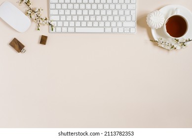Stylish flat lay for a woman's fashion blogger. Workplace of a freelancer or office worker: a laptop, a Cup of black tea, a marshmellow, a  apple flowers. Copy space, top view