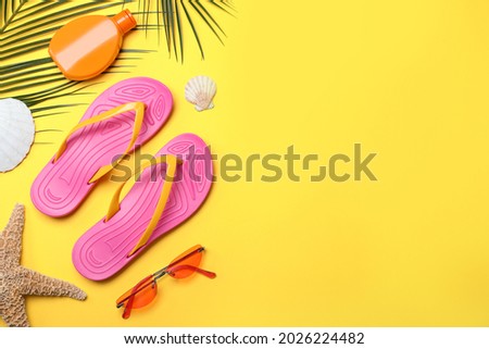 Stylish flip flops and beach objects on yellow background, flat lay. Space for text