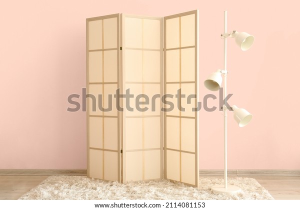 Stylish\
folding screen and floor lamp near wall in\
room