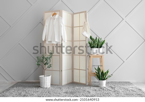 Stylish\
folding screen and houseplants in room\
interior
