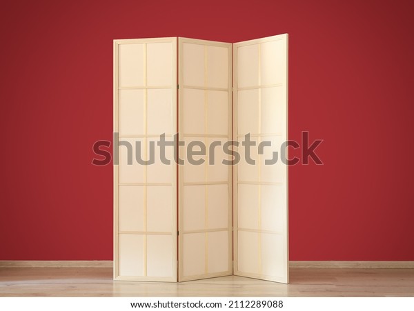 Stylish folding screen near\
red wall