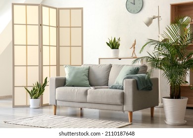 Stylish folding screen near sofa in living room interior - Shutterstock ID 2110187648