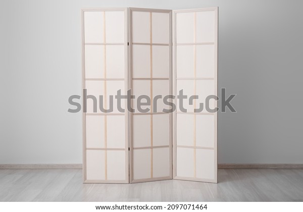 Stylish folding screen in room interior on\
wall background
