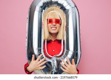 A Stylish, Funny Woman Stands With A Silver Balloon In The Form Of The Number Zero And Happily Smiles With Her Head Stuck Into The Balloon