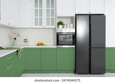 Stylish furniture and modern refrigerator in kitchen. Interior design