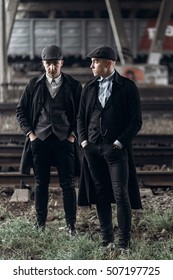 stylish gangsters men, posing on background of railway. england in 1920s theme. fashionable brutal confident group. atmospheric  moments. space for text