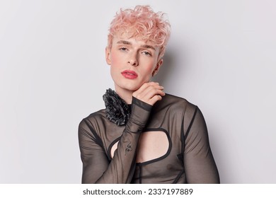 Stylish gay man radiates fashion and self assurance against white studio background. His thoughtful expression and focused gaze at camera conveys sense of inner strength. Gender fluid person - Powered by Shutterstock