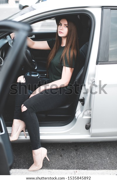 Stylish girl 20-24 year old wearing trendy clothes\
sitting in car closeup.\
