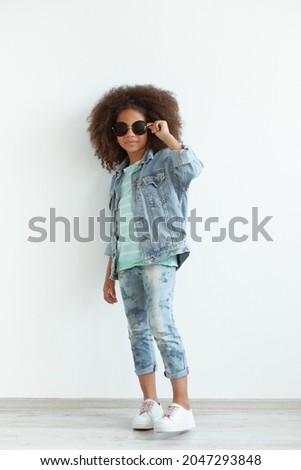 Stylish girl with beautiful curly hair wearing denim clothes and sunglasses