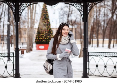 Stylish Girl With Cat Eyes Headband Is Talking On The Phone Outdoors In The Park In Christmas Time. 