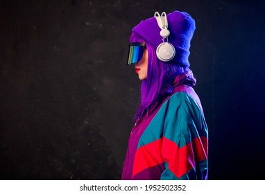 Stylish Girl In Cyber Punk Glasses And 80s Tracksuit With Headphones On Dark Background