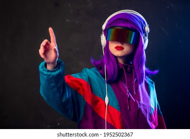 Stylish girl in cyber punk glasses and 80s tracksuit with headphones on dark background 