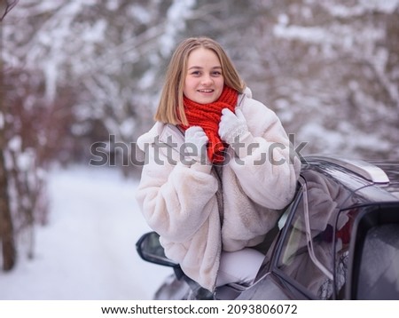  stylish girl happy in her car in winter. Traveling by car. Woman enjoying the winter and snow outside the car. Happiness and travel concept for happy people. New year and Christmas