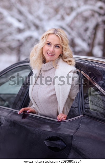  stylish\
girl happy in her car in winter. Traveling by car. Woman enjoying\
the winter and snow outside the car. Happiness and travel concept\
for happy people New year and\
Christmas