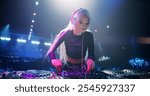 Stylish Girl Performing at a DJ Concert Live on Stage. Talented Music Producer Dancing, Mixing Energetic Dance Hits on Turntables. Young Beautiful Female Engaging with the Crowd