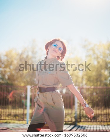 Stylish girl with red hair at the playground in the rays of sunlight.