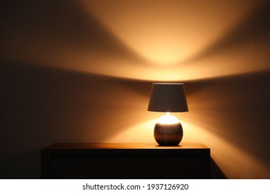 Stylish glowing  night lamp on table in room. Space for text