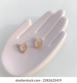 Stylish gold earrings on a plaster mold in the form of a hand palm. - Shutterstock ID 2282623419