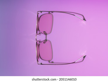Stylish gold   pink eye glasses and shadow purple   pink gradient background  Flat lay style  top view  Copy space for your text  Minimal summer concept 