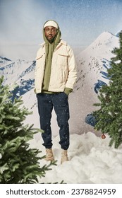 stylish good looking man posing under snowfall with hands in pockets looking at camera, winter