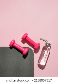 Stylish gray, water bottle and pink fitness training and gym flat lay. Top view of gray sport mat and pink dumbbells on pink background. Set for pilates, fitness with copy space. Vetical - Shutterstock ID 2138057317