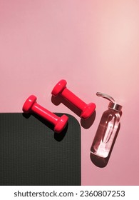 Stylish gray, water bottle and pink fitness training and gym flat lay. Top view of gray sport mat and pink dumbbells on pink background. Set for pilates, fitness with copy space. Vetical - Shutterstock ID 2360807253