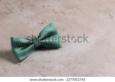 Stylish green bow tie on gray textured background, space for text
