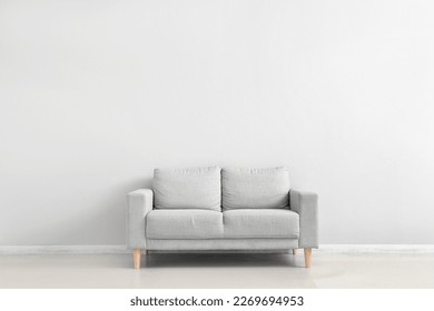 Stylish grey sofa near white wall - Shutterstock ID 2269694953