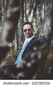 Stylish groom posing in the woods