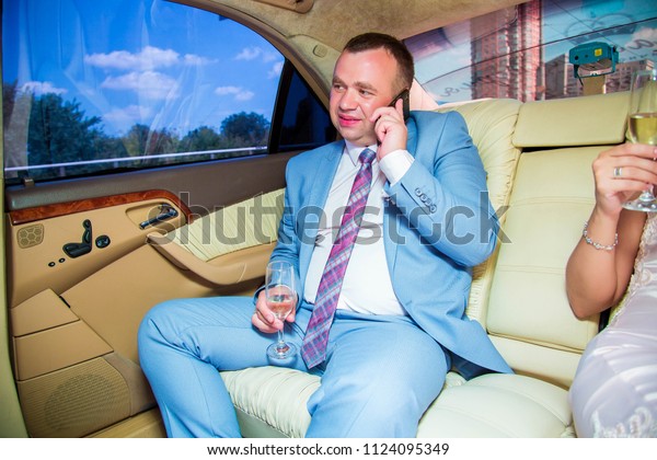 Stylish groom in  suit, communicate on mobile\
phone in luxury\
limousine