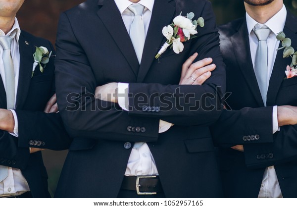 stylish groom in suit posing with groomsmen in\
garden on wedding day. luxury men in  rich outfits standing\
together. friendship
