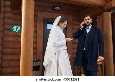 Stylish groom talks  by the phone standing with a bride behind a wooden house - Powered by Shutterstock