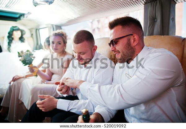 Stylish groomsman or best man of groom and\
bridesmaids inside limousine at wedding\
party.