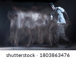 Stylish guy breakdancer dancing hip-hop in studio on black background. Long exposure shot