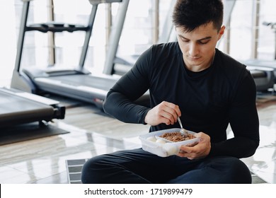 Stylish Guy In The Gym Relaxing On The Floor And Eating Healthy Food. Healthy Lifestyle.