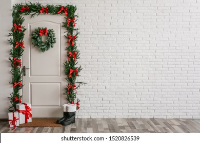Stylish hallway interior with decorated door and Christmas gifts, space for text
