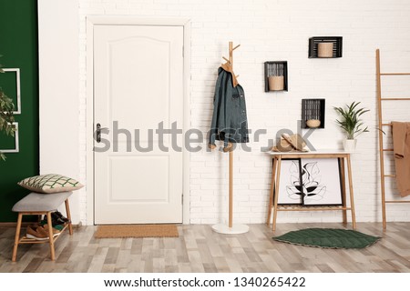 Stylish hallway interior with shoe storage bench, hanger stand and table