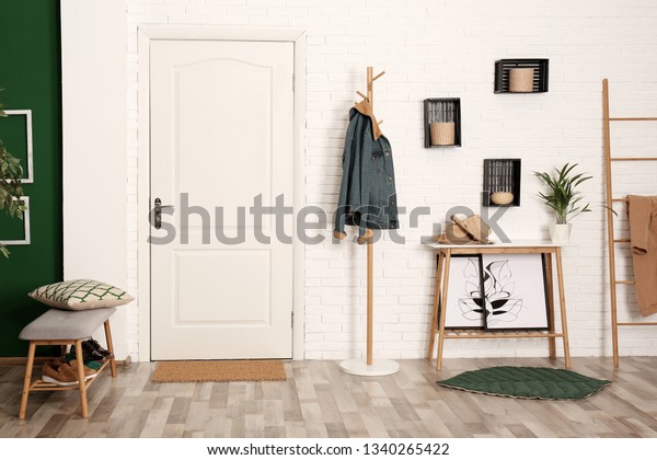 Stylish hallway interior with shoe storage bench,\
hanger stand and table
