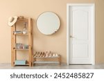 Stylish hallway interior with wooden storage shelf, mirror, footwear collection and spring flowers