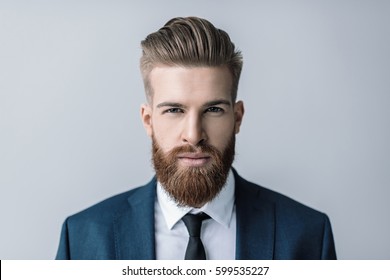 Stylish handsome bearded businessman looking at camera isolated on grey - Shutterstock ID 599535227