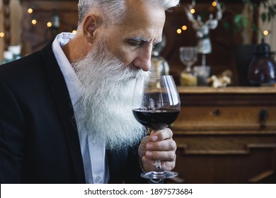 Stylish And Handsome Bearded Senior Man Drinking Red Wine