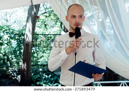 stylish handsome emcee performing speech for toast at wedding reception