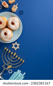 Stylish Hanukkah table arrangement. Top view vertical image of traditional Jewish meal - sufganiyot, Star of David, menorah, and dreidel game on blue background, space for text or advertising