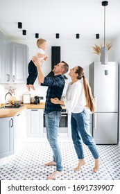 Stylish happy family is having fun at home in the kitchen. Parents play with their baby
