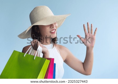 Stylish happy smiling anonymous young Asian woman in urban shopping adventure pointing up five fingers on isolated background, concept of fifty percent sale special offer