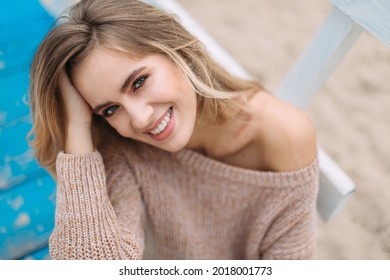 Stylish happy young woman wearing beige sweater . portrait of smiling girl looking at the camera. close-up portrait of girl with natural beauty.